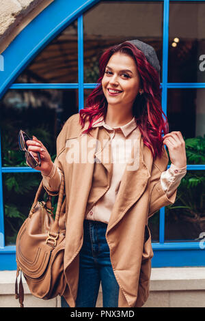 Elegante giovane donna avendo divertimento all'aperto. Moda autunno vestito. Felice bellissimo modello che mostra la linguetta Foto Stock