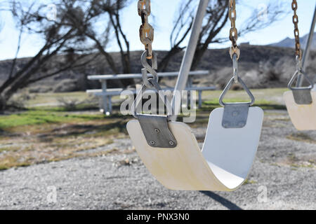 Swing bianco in un parco giochi abbandonato Foto Stock