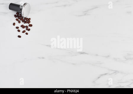 Vista superiore di caffè nero manomissione e di chicchi di caffè tostati su marmo bianco dello sfondo. Lay piatto con copia spazio. Foto Stock