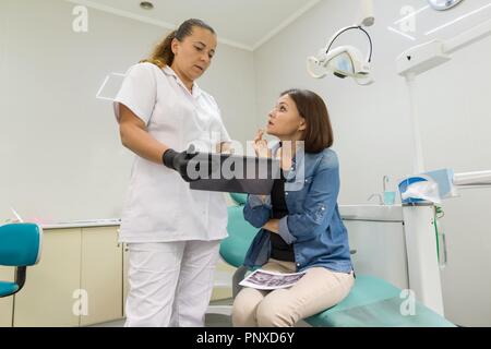 Dentista che mostra un paziente il suo denti x-ray. Sanitario, medico e odontoiatria concetto. Foto Stock