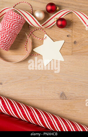 Semplice e in stile country regalo di Natale carta da imballaggio, nastri, decorazioni e blank gift tag in legno rustico sfondo di legno Foto Stock