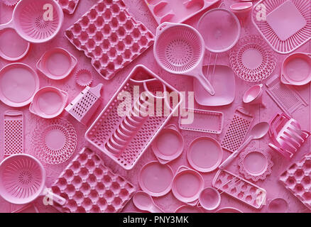 Close up lay piatto di diverso colore rosa dipinto di utensili da cucina e utensili, grattugia, cucchiaio, uova di cartone, plastica piastre monouso, elevati vista dall'alto, Foto Stock