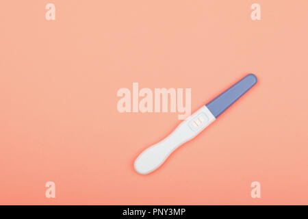 Chiudere uno positivo (gravidanza) Risultato test di gravidanza pastello su carta rosa, sfondo elevato angolo di alta vista, direttamente al di sopra di Foto Stock