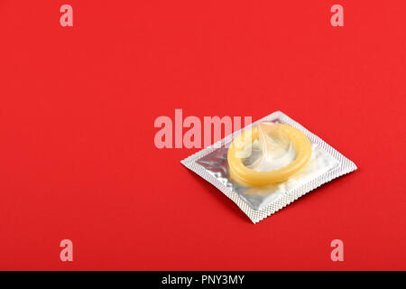 Chiudere un preservativo di lattice su argento wrap pack su vivid sfondo rosso con copia spazio, elevata angolo visuale, direttamente sopra Foto Stock