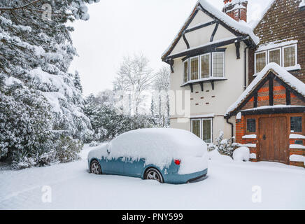 Auto blu parcheggiato nel comando di un grande Tarrant house di Woking, Surrey, Regno Unito ricoperto di neve durante forti nevicate in inverno Foto Stock