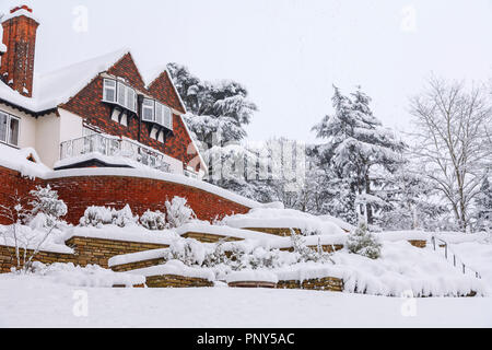 Giardino posteriore vista di una grande casa Tarrant e coperti di neve terrazzamenti a Woking, Surrey, Regno Unito ricoperto di neve durante forti nevicate in inverno Foto Stock