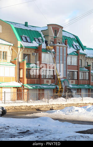 Il servizio di pulizia pulisce la neve dal tetto della casa. Foto Stock