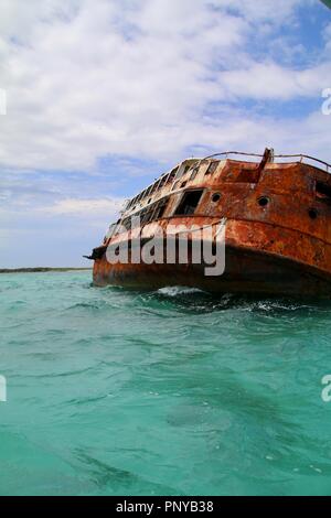 Un arrugginito relitto recante su di esso 's lato nei Caraibi, devastata da un uragano Foto Stock