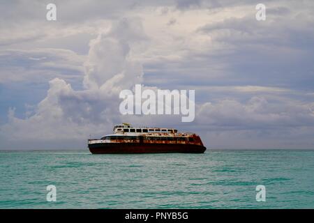 Nave naufragata durante un uragano nei Caraibi con una tempesta edificio dietro di essa Foto Stock