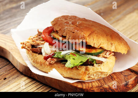 Tirate la carne di maiale panini con salsa barbecue, cavolo e sottaceti sul tavolo di legno. Foto Stock