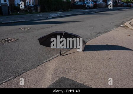 Un ombrello rotto laici in strada Foto Stock