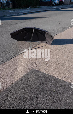 Un ombrello rotto laici in strada Foto Stock