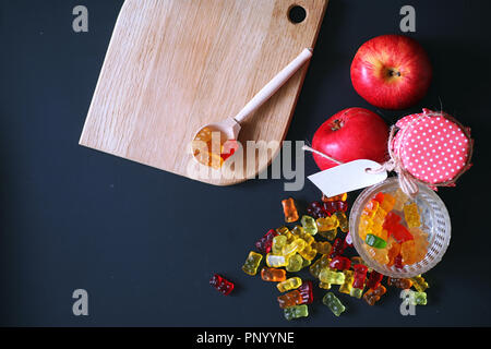 La marmellata di arance in un vaso sul tavolo. Caramelle in una ciotola su una ba nero Foto Stock