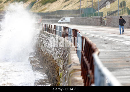 Colwyn Bay, Regno Unito settembre 2018UK Meteo: Un autunnale di sentire nell'aria sull'equinozio d'autunno il primo giorno di autunno con basse temperature e condizioni ventose nella località costiera comune di Colwyn Bay, il Galles del Nord. Una persona che cammina indietro dalla parete del mare come le onde in crash a Colwyn Bay, il Galles del Nord Foto Stock