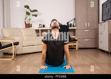 I giovani adulti facendo yoga cobra pongono sulla sua casa piano. Home te Foto Stock