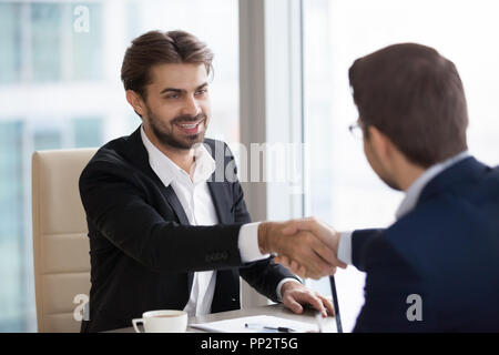 Sorridente business partner si stringono la mano durante la riunione Foto Stock