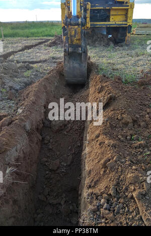 Vista da sopra al lavoro trattore escavatore scavare una trincea. Foto Stock