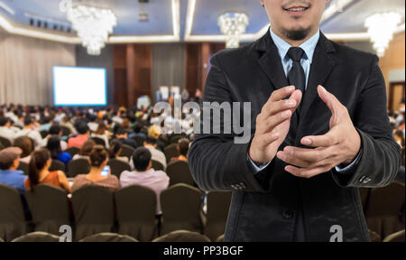 Closeup imprenditore battimani e sorridente sul Riassunto foto sfocata della sala conferenze o sala seminario con gli altoparlanti sul palco e partecipante backgrou Foto Stock