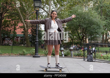 Foto di un attraente ragazza a cavallo su uno skateboard in Washington Square Park di New York City. Foto Stock