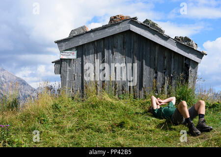 Holzgau: escursionista uomo in appoggio giacente presso il monte prato, capanna, Lechtal Valley, Tirol, Tirolo, Austria Foto Stock