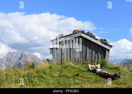 Holzgau: escursionista uomo in appoggio giacente presso il monte prato, capanna, Lechtal Valley, Tirol, Tirolo, Austria Foto Stock