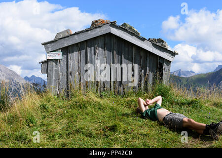 Holzgau: escursionista uomo in appoggio giacente presso il monte prato, capanna, Lechtal Valley, Tirol, Tirolo, Austria Foto Stock