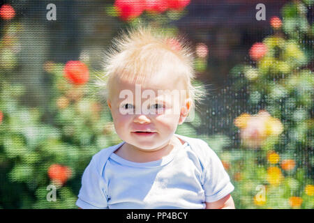 Carino piccolo ragazzo con electricy statico capelli, avente il suo spiritoso ritratto preso all'aperto su un trampolino Foto Stock