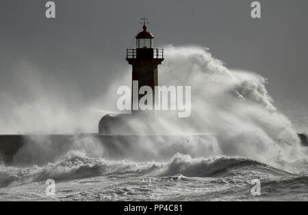 Grande dettagliate onde tempestose oltre il vecchio faro e pier Foto Stock