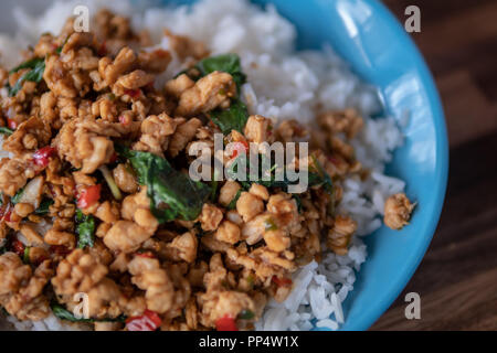 Popolare piatto tailandese, il tampone di Kra Prao Kai o piccante Pollo fritto con basilico e rabboccato il riso al gelsomino Foto Stock