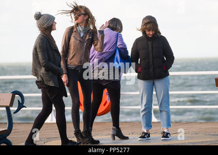 Aberystwyth, Wales, Regno Unito. Domenica 23 settembre 2018. Regno Unito Meteo: gente camminare lungo la passeggiata sono buffeted spazzate dal vento dal forte vento su un soleggiato ma blustery Equinox domenica pomeriggio a Aberystwyth sulla West Wales coast. Oggi è l'ultimo giorno di estate Astronomico - quando il giorno e la notte sono di uguale lunghezza. Da domani le notti sono più lunghi dei giorni, segnando l inizio di inverno astronomico nell emisfero nord Foto © Keith Morris / Alamy Live News Foto Stock