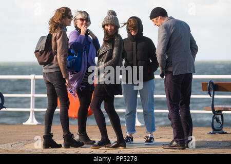 Aberystwyth, Wales, Regno Unito. Domenica 23 settembre 2018. Regno Unito Meteo: gente camminare lungo la passeggiata sono buffeted spazzate dal vento dal forte vento su un soleggiato ma blustery Equinox domenica pomeriggio a Aberystwyth sulla West Wales coast. Oggi è l'ultimo giorno di estate Astronomico - quando il giorno e la notte sono di uguale lunghezza. Da domani le notti sono più lunghi dei giorni, segnando l inizio di inverno astronomico nell emisfero nord Foto © Keith Morris / Alamy Live News Foto Stock