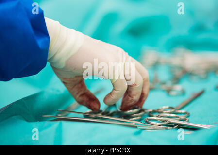 Chirurgo raccolta a mano uno strumento dal vassoio di strumenti chirurgici Foto Stock