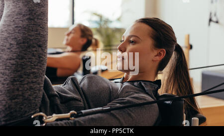 Donna che si allena su una macchina fitness. donne fitness che fanno esercizi di stretching utilizzando pilates attrezzature per lo stretching. Foto Stock