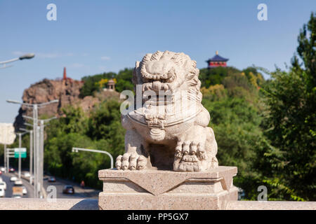 Leone di pietra Xi Daqiao ponte con Hong Shan (Hongshan o Montagna Rossa) Parco visto in background, Urumqi, Xinjiang, Cina Foto Stock