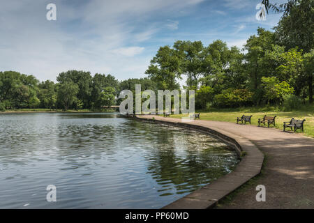 Tranquilla vista sul lago nel parco pubblico di Stanley Park di Blackpool, Lancashire, Regno Unito su un soleggiato giugno mattina con nessun popolo, percorso & panche.. Foto Stock