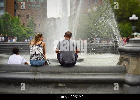 New York, NY; Giugno 2017: un giovane si siede insieme presso la fontana di Washington Square Park Foto Stock