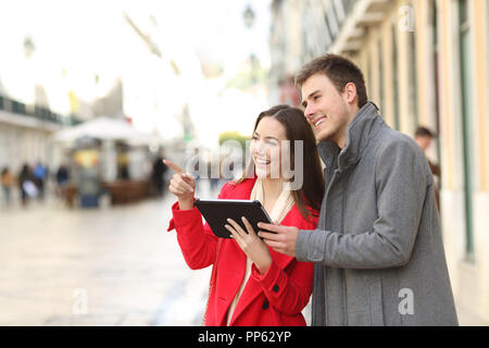 Coppia felice rivolto lontano utilizzando una pastiglia per la strada di una vecchia città Foto Stock