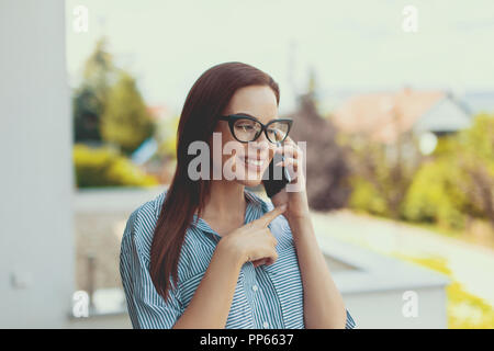 Giovani fiduciosi realtor chiamando con sorriso toothy negoziare sui prezzi all'aperto Foto Stock