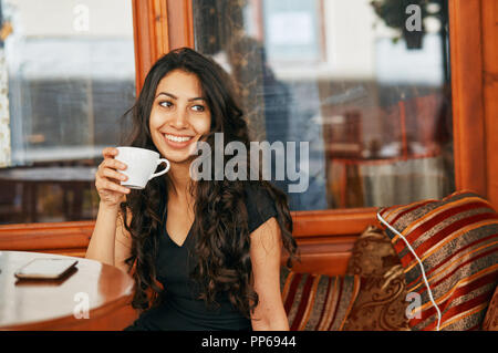 Giovane donna araba di bere il caffè in un bar Foto Stock