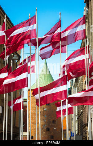 Lettonia Riga bandiera, vista della nazionale lettone bandiere sul display al centro della riga con il tetto della Torre della Polvere in background, Lettonia. Foto Stock