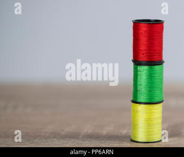 Tre thread colorati stand verticlal sulla tabella di marrone. Foto Stock