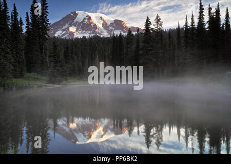 Primo bagliore di luce su Washington Mt Rainier dal appropriatamente chiamato laghi di riflessione in Mount Rainier National Park. Foto Stock