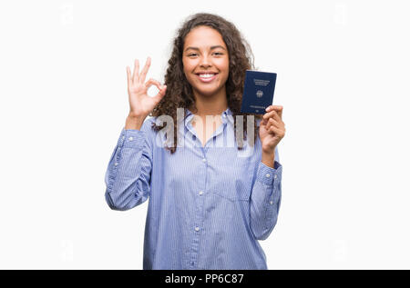 Giovane donna ispanica tenendo il passaporto della Germania facendo segno ok con le dita, simbolo eccellente Foto Stock