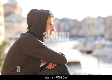 Vista laterale verticale di un pensieroso teen boy contemplando una porta in vacanza Foto Stock