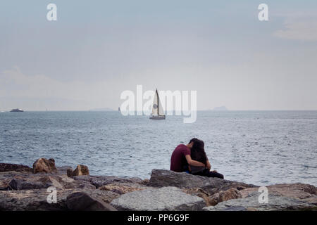 Vista di un irriconoscibile coppia giovane seduto sulle rocce dal Bosforo. Immagine è catturata nel quartiere chiamato Moda situato sul lato Asiatico Foto Stock