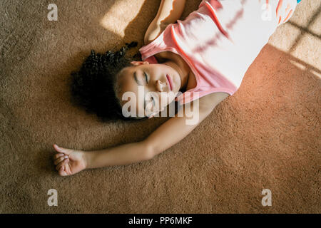 La ragazza che posa in salotto tappeto sotto la luce diretta del sole Foto Stock