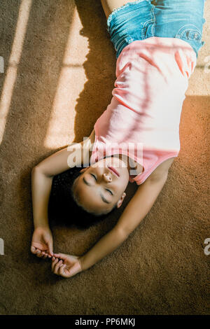 La ragazza che posa in salotto tappeto sotto la luce diretta del sole Foto Stock