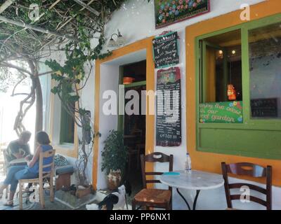 Grecia, la tranquilla, bella e tradizionale isola di Sikinos. Un piccolo e rilassante cafe nella citta' vecchia. La gente si rilassa all'ombra con bevande. Foto Stock