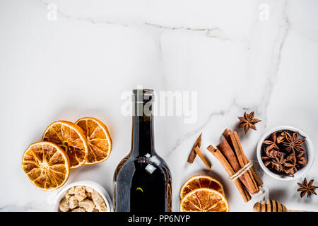 Ingredienti per il tradizionale autunno drink, vino mulled cocktail - vino rosso, arance raffermo, lo zucchero di canna, miele, cannella, spezie anice, su marmo bianco Foto Stock