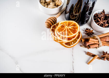 Ingredienti per il tradizionale autunno drink, vino mulled cocktail - vino rosso, arance raffermo, lo zucchero di canna, miele, cannella, spezie anice, su marmo bianco Foto Stock